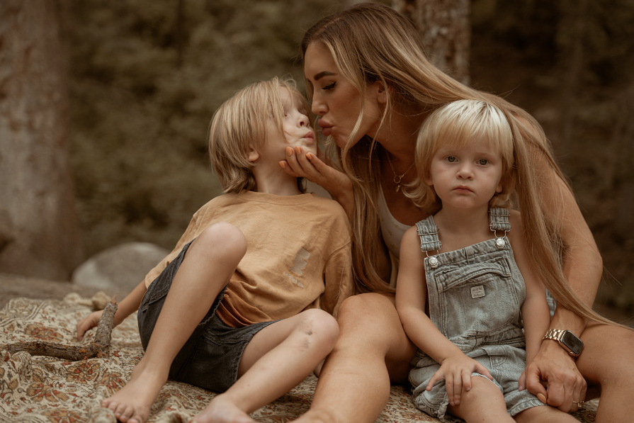 Mother with two blonde sons giving a kiss to son